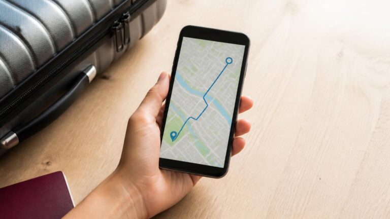 Pessoa usando um smartphone com mapas e itinerário de viagem na tela, com mala e passaporte ao lado.
